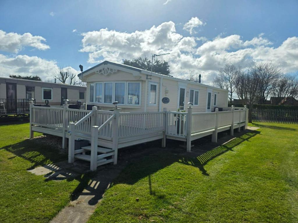 a white house with a porch in a yard at Millfields caravan park I9 in Skegness