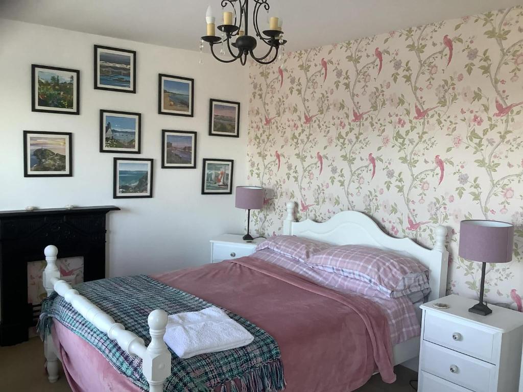 a bedroom with a bed and a wall with wallpaper at Glan Morfa in Morfa Nefyn