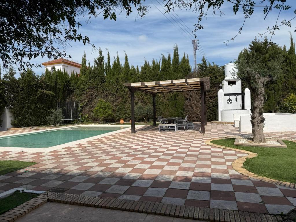 a patio with a pool and a wooden pergola at Villa El Carmen in Sanlúcar la Mayor
