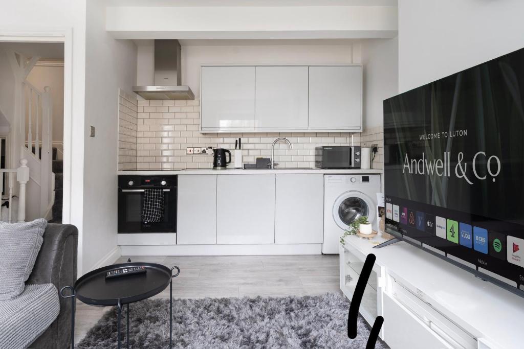 a kitchen with white cabinets and a table in a room at Jasmin Place in Luton