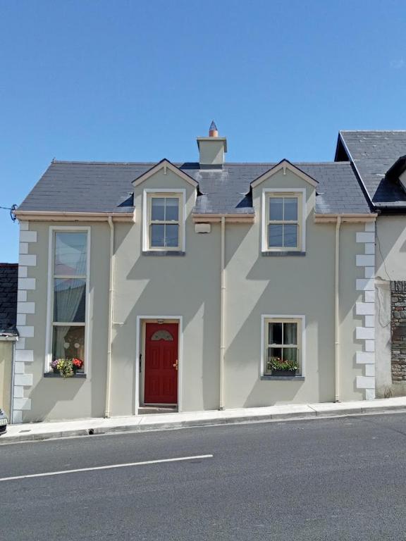 a white house with a red door on a street at Roseville in Limerick