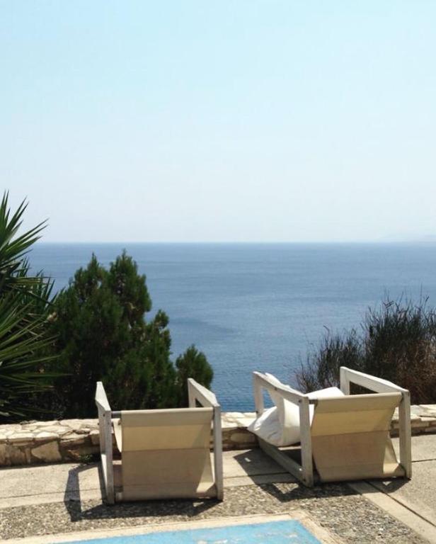 two white chairs sitting next to a swimming pool at Zen Townhouse - Infinity Seaview in Palaiokastro