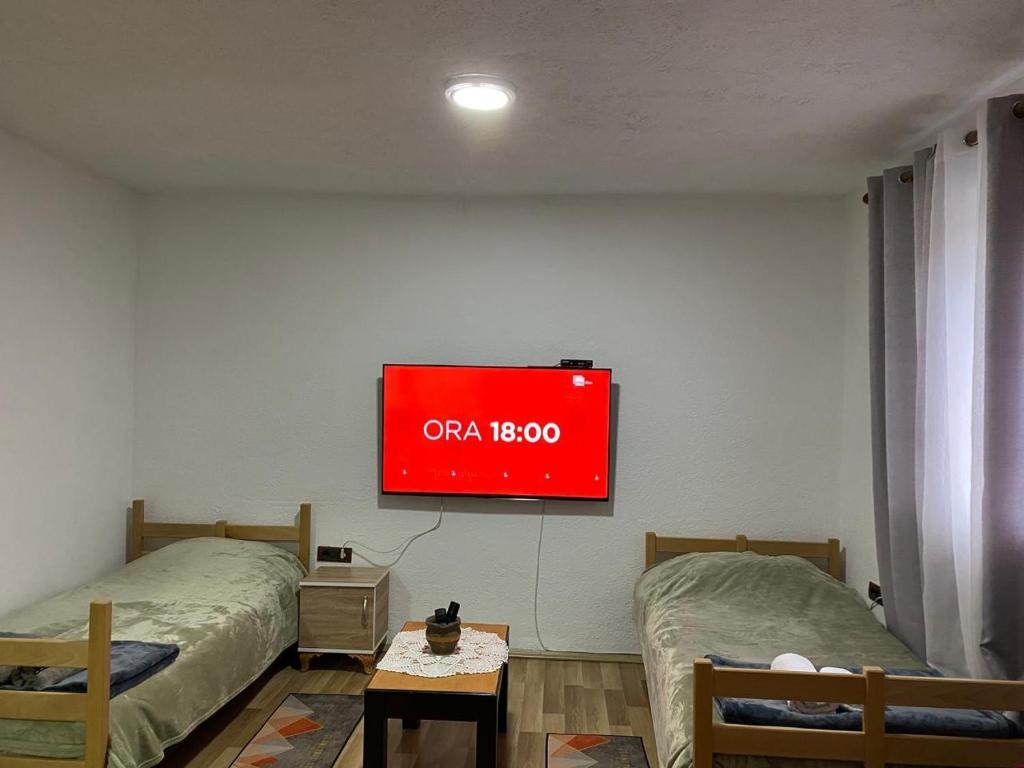 a tv hanging on a wall with two beds at Necaj Apartment in Fierzë