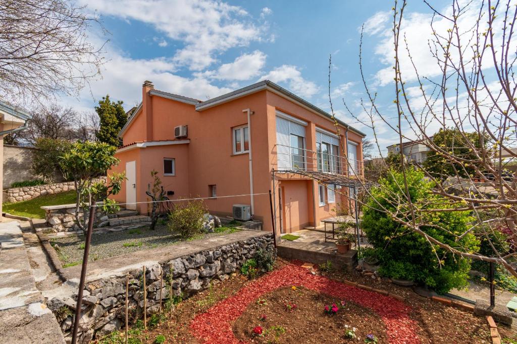 an orange house with a stone wall at Apartment Tena in Kraljevica