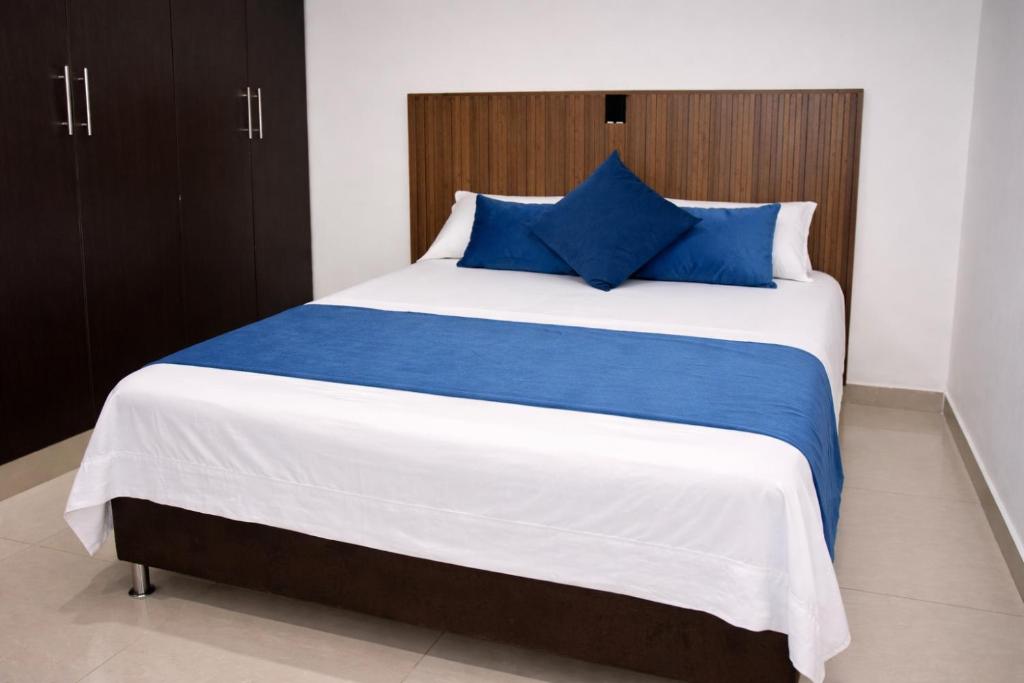 a bedroom with a large bed with blue pillows at Hotel Barcelona in Montería