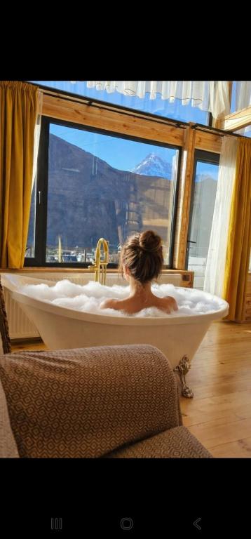 a woman in a bath tub in a room with a window at mood villa kazbegi in Kazbegi