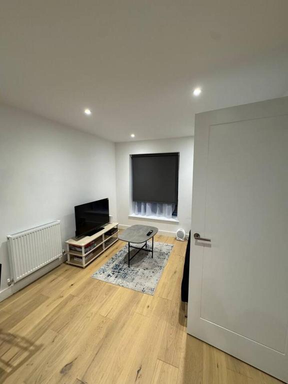 a living room with a table and a flat screen tv at Tranquil 3BD in Watford in Watford