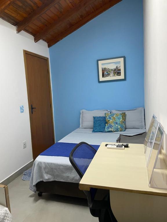 a bedroom with a blue wall and a bed with a desk at Hostel Recanto Verde - Conforto e Tranquilidade em Campo Grande in Campo Grande