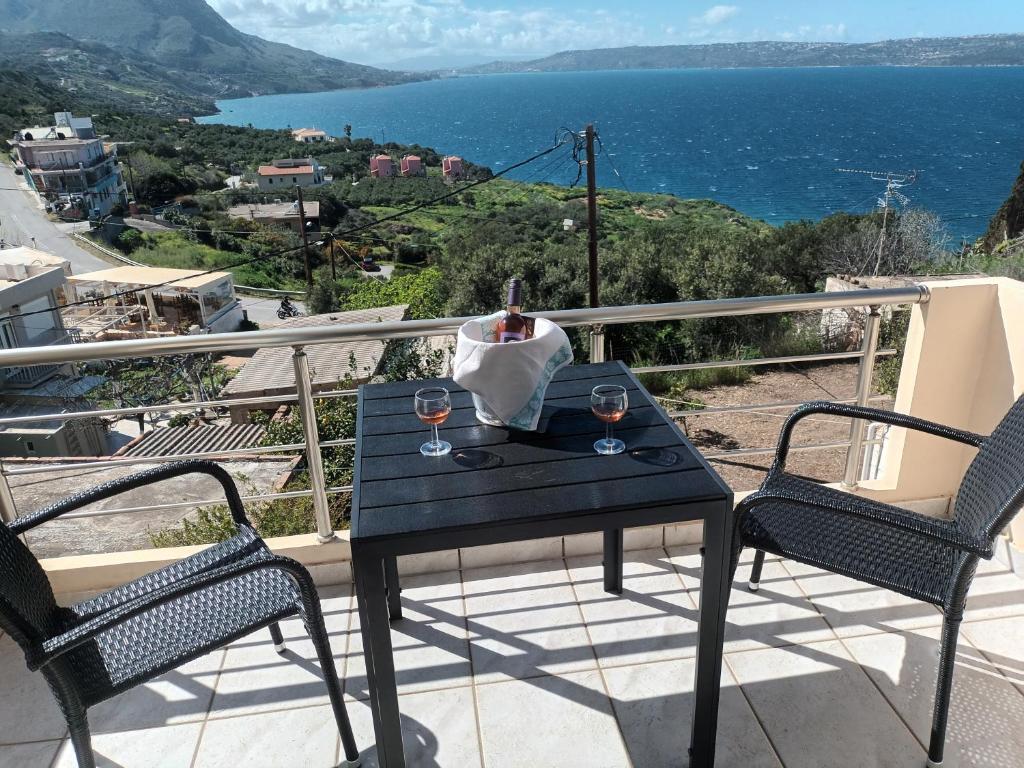 a table with two glasses of wine on a balcony at Olympic View Guesthouse in Kalami