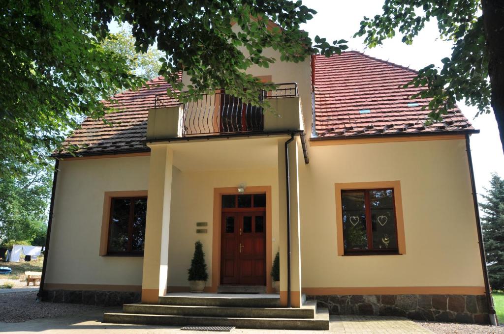 a small white house with a red roof at Dworek Bogdanka in Trzebin
