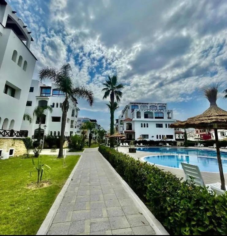 a resort with a swimming pool and palm trees at Luxushaus in Martil
