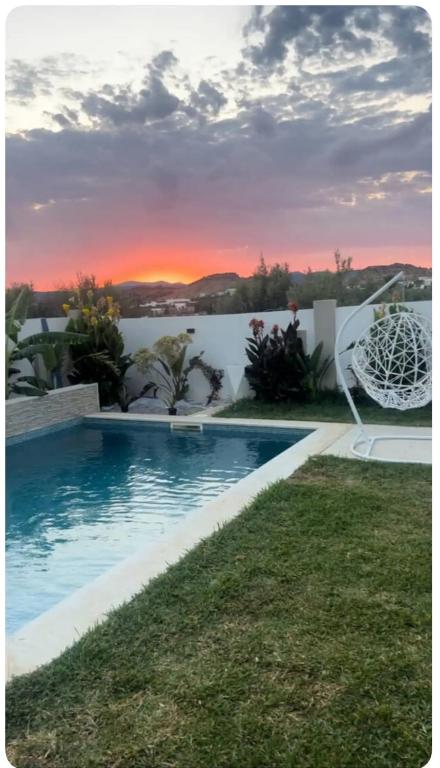 a villa with a swimming pool and a sunset at Villa Bianca Sidi Jedidi in Sidi Jedidi