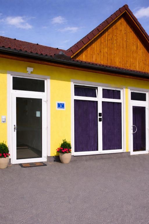 a yellow building with two doors and two potted plants at Apartment Hofacker in Pernegg an der Mur