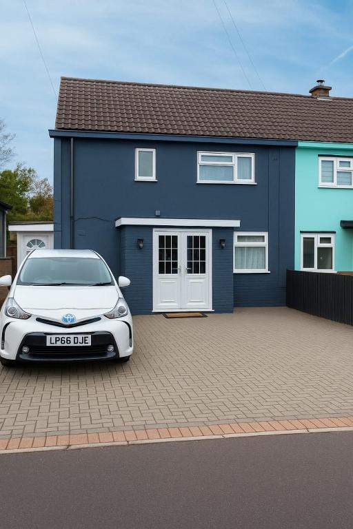a white car parked in front of a blue house at Nayla House Cozy 4BR with Garden & Parking in Moffat