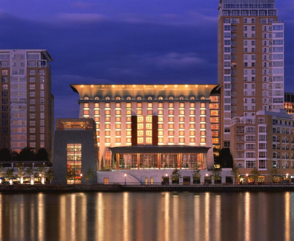 un grand bâtiment avec des lumières sur lui, à côté d'une masse d'eau dans l'établissement Canary Riverside Plaza Hotel, à Londres