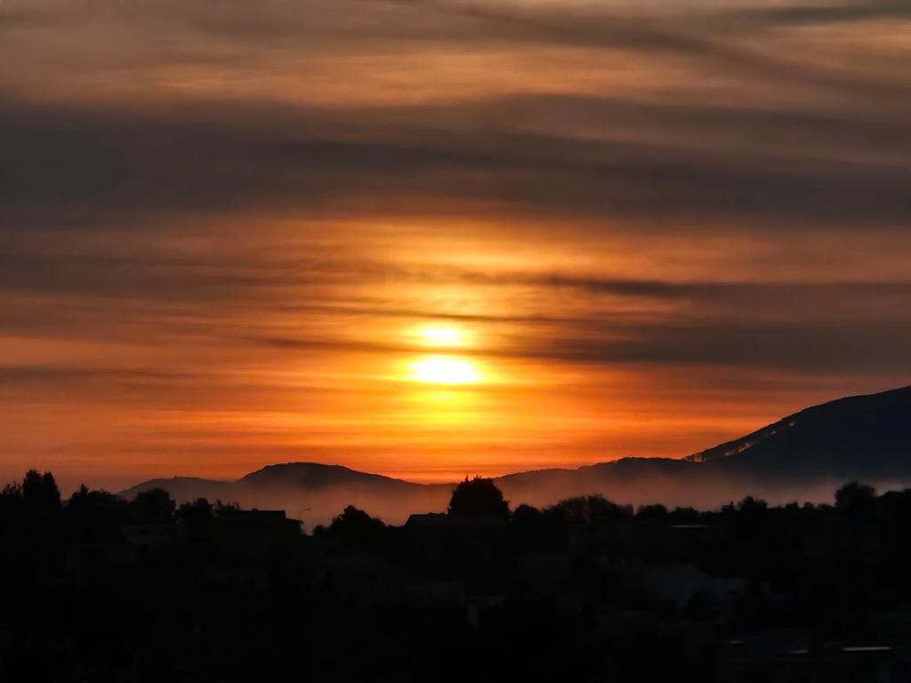 a sunset with the sun rising over the mountains at Apartmán Orchidea in Prešov