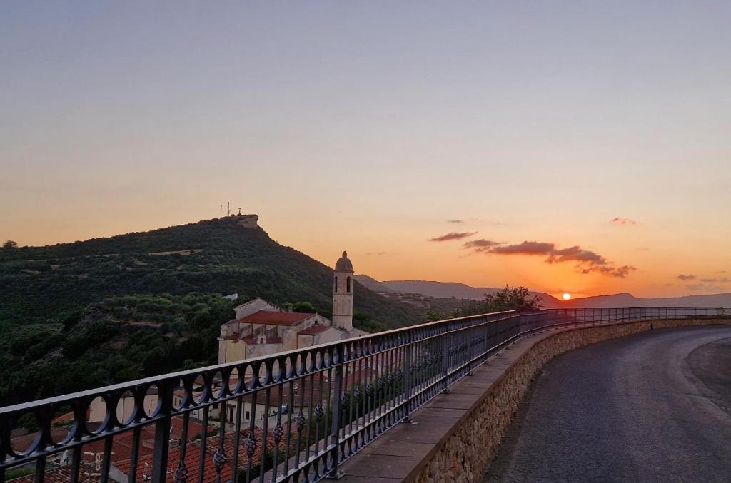 a sunset over a road with a church on a hill at Il Lentisco in Codrongianos