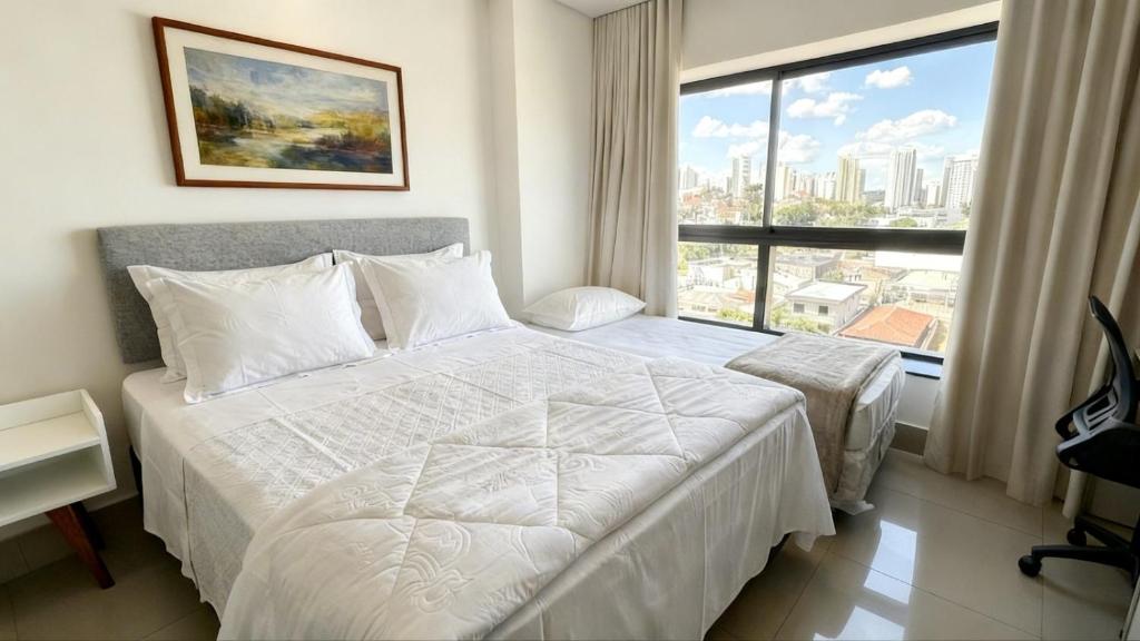 a bedroom with a white bed and a large window at Studio Amplo e Aconchegante com 2 Camas in Campo Grande