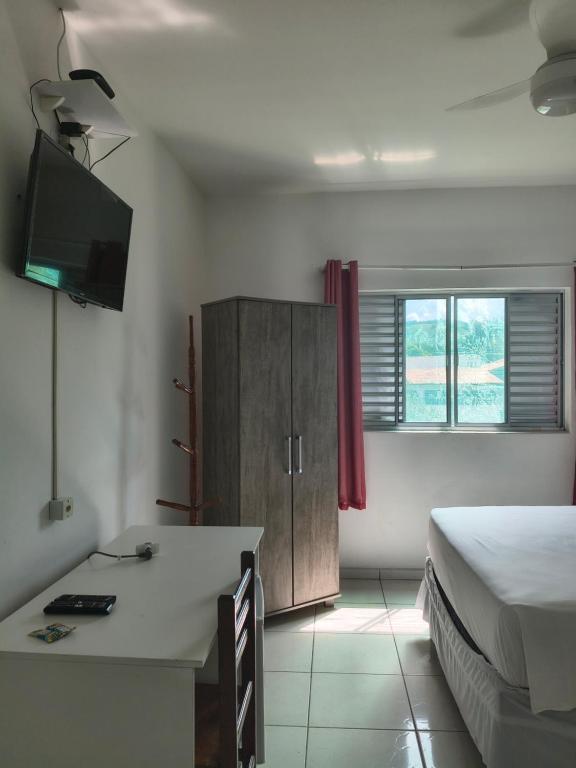 a bedroom with a bed and a desk and a television at Pousada Esperança - Areias SP in Areias