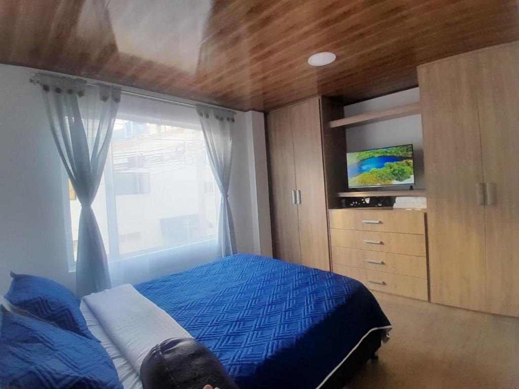 a bedroom with a blue bed and a window at Alojamiento y Confort in Tunja