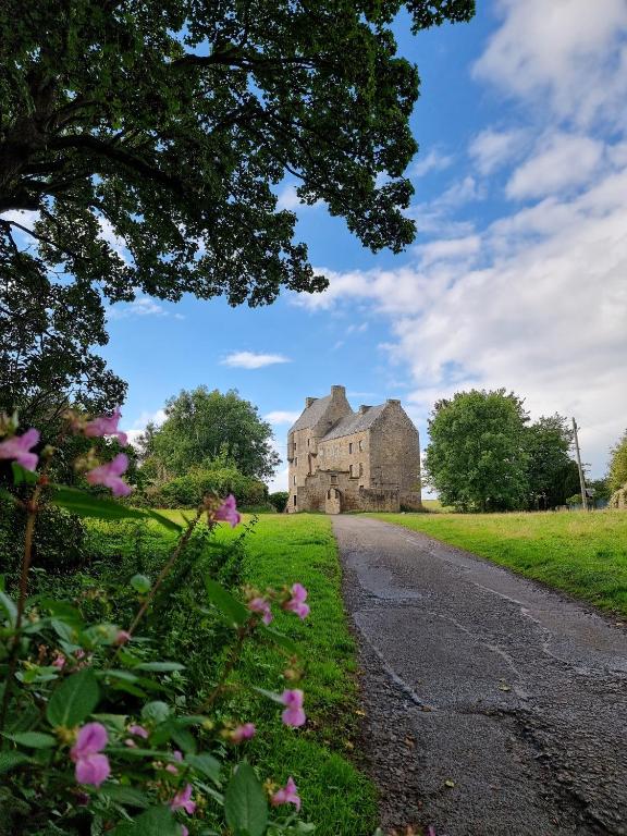 an old castle with pink flowers on the side of a road at Midhope Castle Cottages in Queensferry
