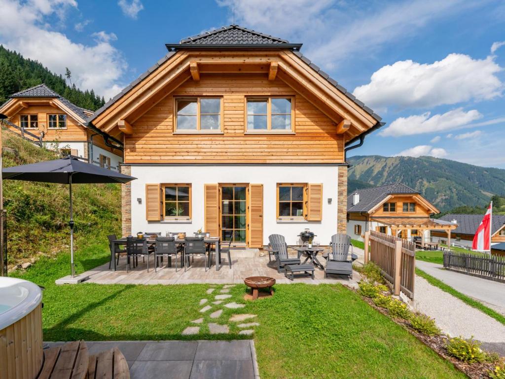 a log home with a patio with a table and chairs at Alpenjoy Lodge in Donnersbachwald