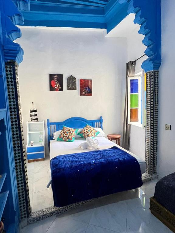 a blue and white bedroom with a bed and a mirror at maison bleu hajja in Tangier