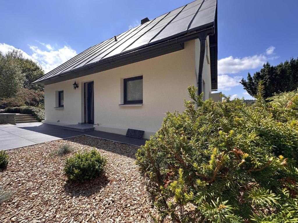 a white house with a black roof and some bushes at Zum wilden Jakob in Stadlern