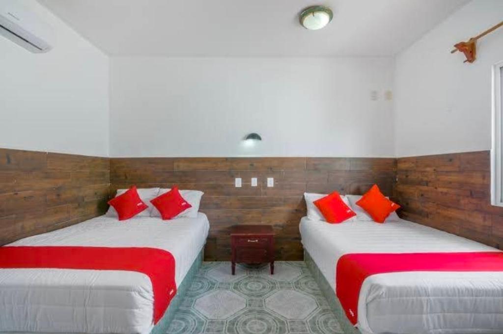 two beds in a room with red pillows at Hotel Palma Real in Francisco Uh May