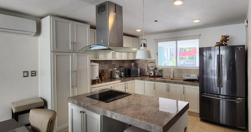 a kitchen with white cabinets and a stainless steel refrigerator at Beautiful house with a pool in Mérida