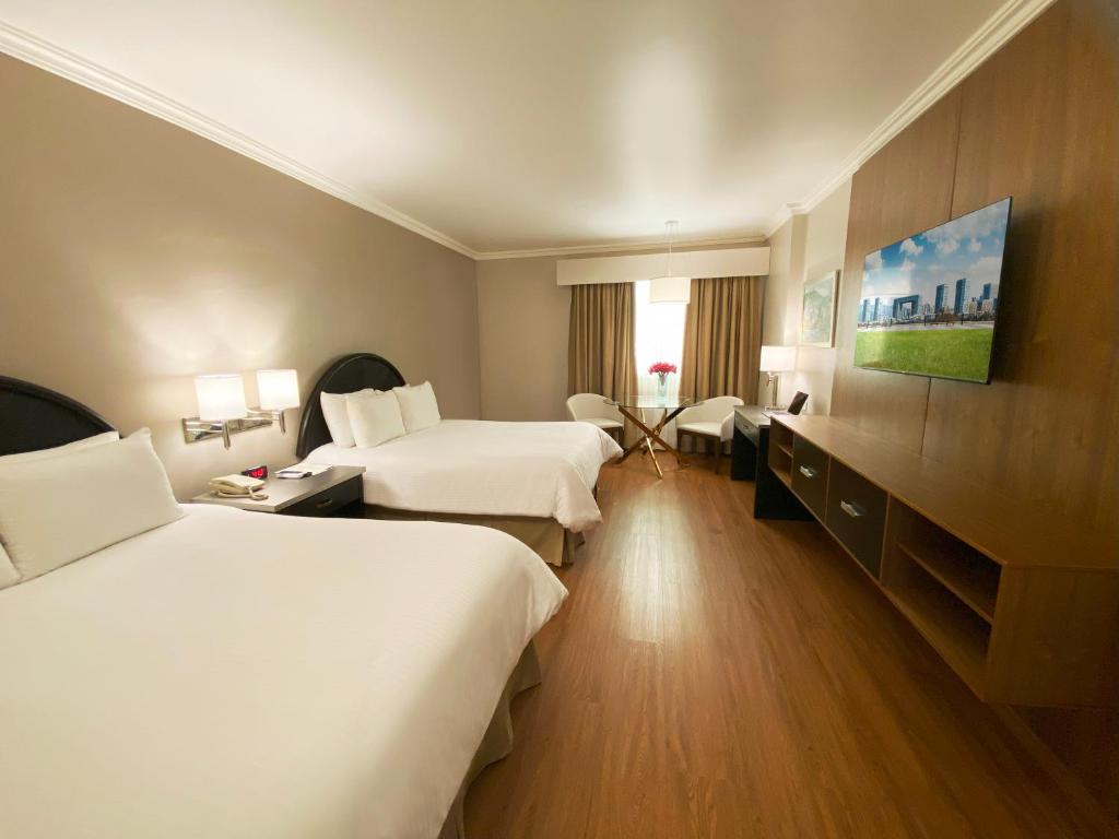 a hotel room with two beds and a tv at Plaza de Oro in Monterrey