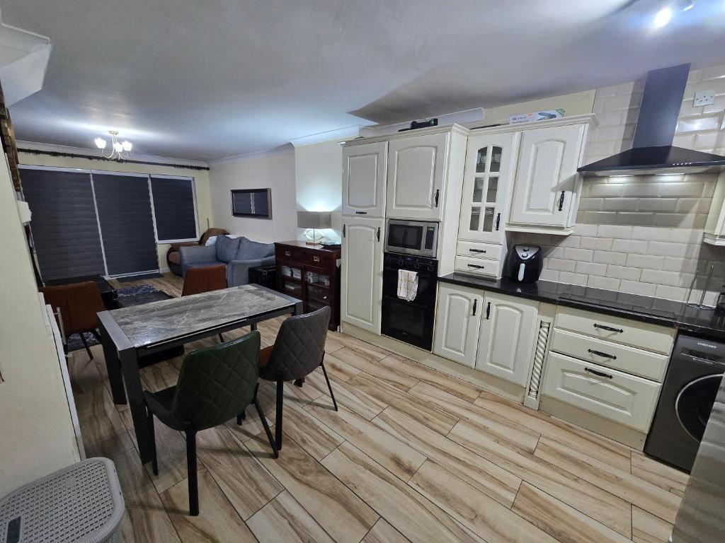 a kitchen with white cabinets and a table and a living room at Gracian OMB Ongar 3 Bed in Dublin