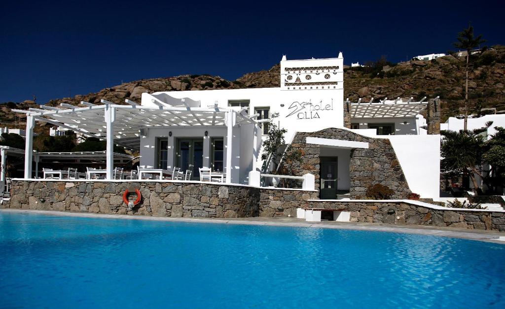 a building with a swimming pool in front of a house at Olia Hotel in Tourlos