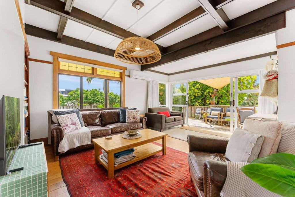 a living room with a couch and a table at Cabbage Tree Cottage in Papamoa