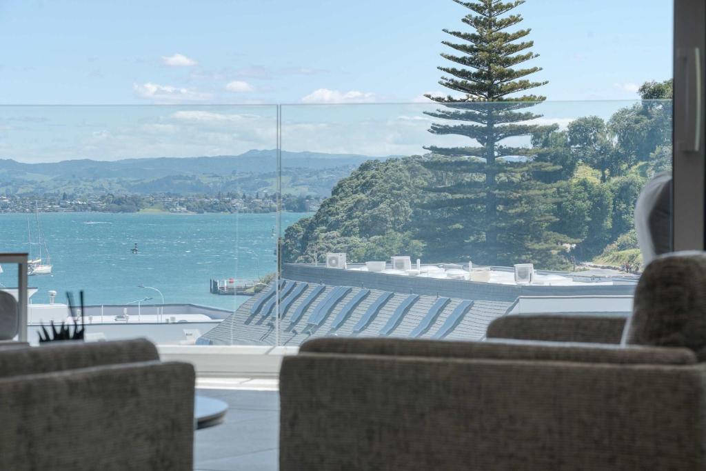 a room with a view of the water and a tree at Oceanside Belle in Mount Maunganui