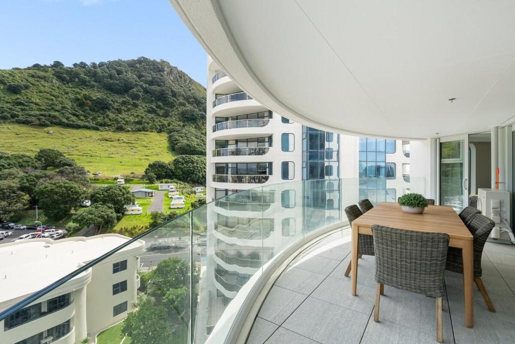 a balcony with a table and chairs and a building at Executive Oceanside Apartment in Mount Maunganui