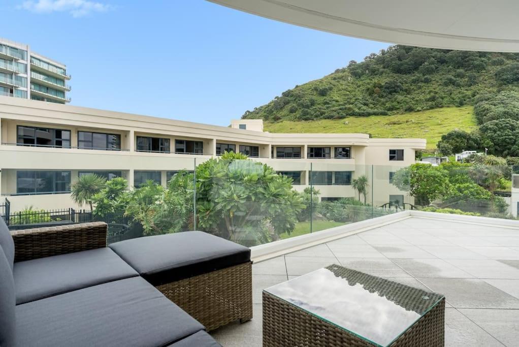 a patio with a couch and a building at Oceanside Apartment with Pool Views in Mount Maunganui