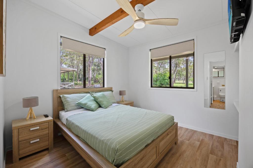 a bedroom with a bed and a ceiling fan at Agnes Bush Cabins in Agnes Water