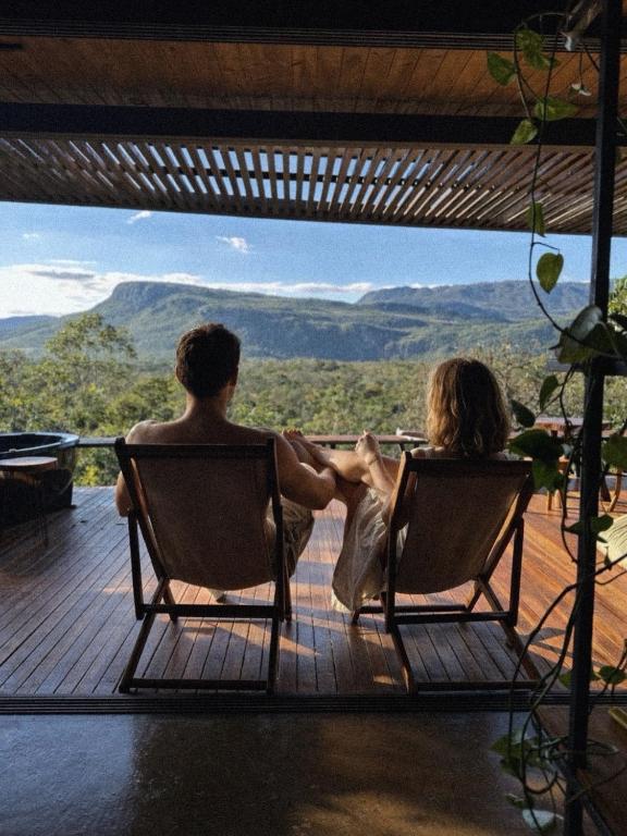 a man and woman sitting in chairs on a deck at A nossa casa da arvore in Cavalcante