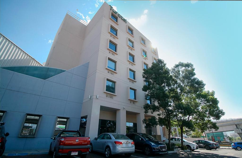 a white building with cars parked in front of it at Hotel Turotel Morelia in Morelia