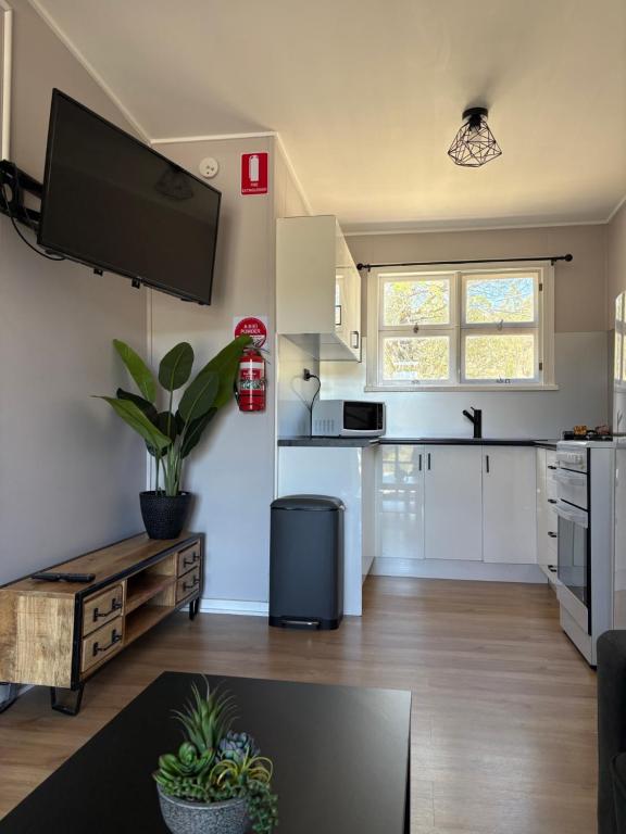 a kitchen with white cabinets and a flat screen tv on the wall at Cooma Holiday Park in Cooma