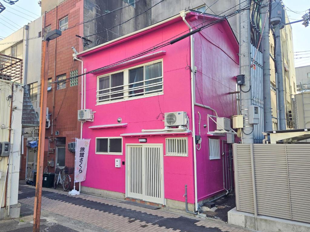 a pink building on the side of a street at 旅館さくら in Takamatsu