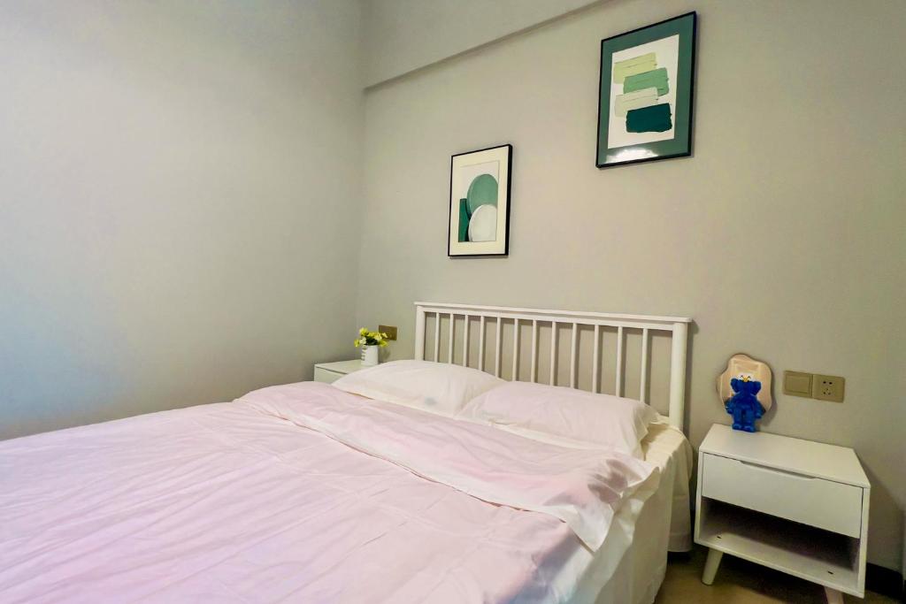 a white bed in a bedroom with two pictures on the wall at Luke Cloud RSJA-s store in Gongche