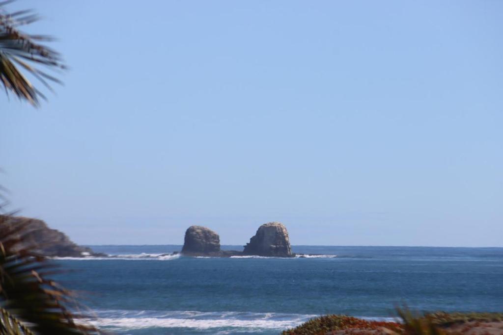 a view of two large rocks in the ocean at Costa Lodge Pichilemu in Pichilemu