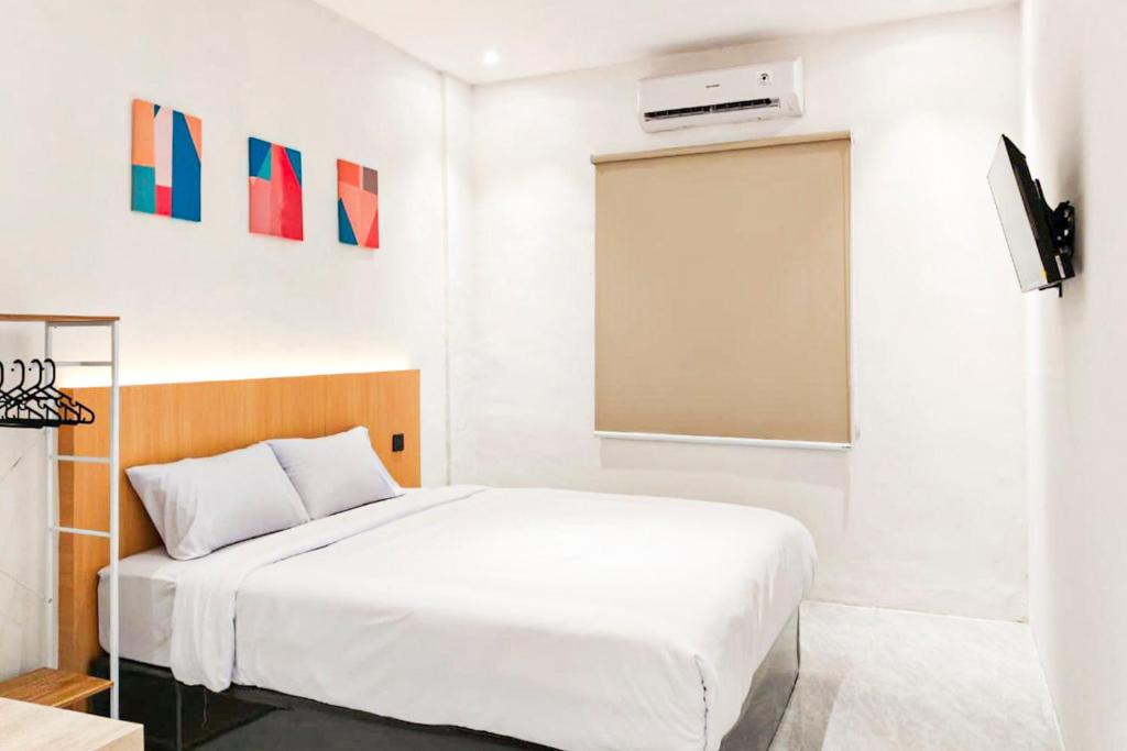 a white bedroom with a bed and a projector at Adi Inn Homestay RedPartner in Sunggal