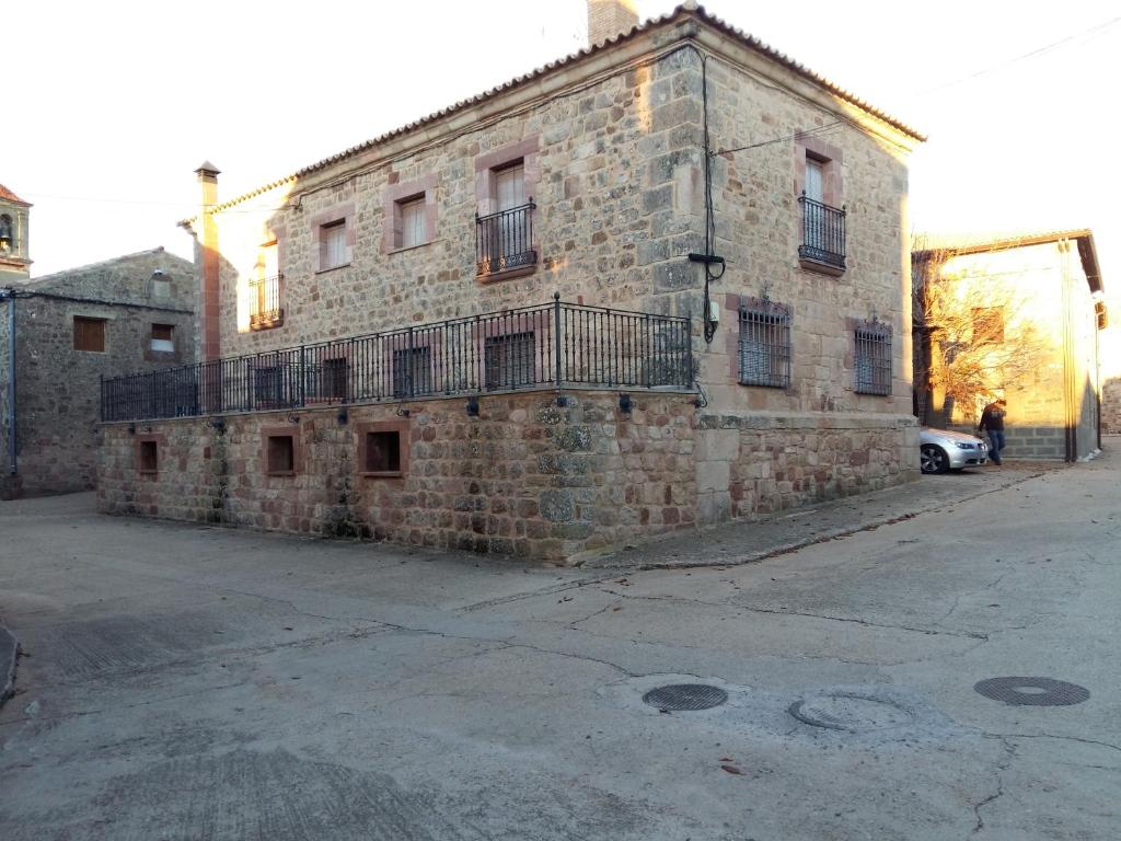 um antigo edifício de tijolos com uma varanda numa rua em Casa Júnez em Romanillos de Medinaceli