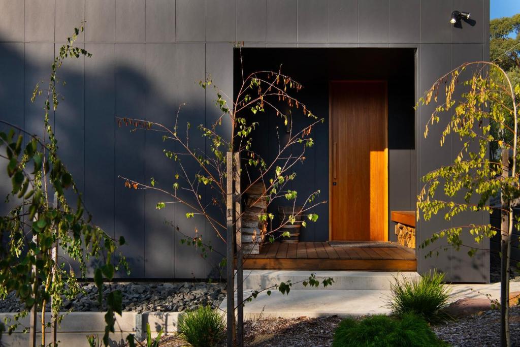 a house with a wooden door and a tree at Banjo Treehouse in Hepburn Springs