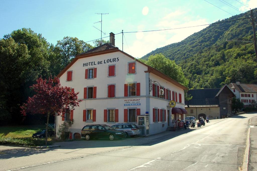 um edifício branco com persianas vermelhas numa rua em Hôtel de l'ours em Vuiteboeuf