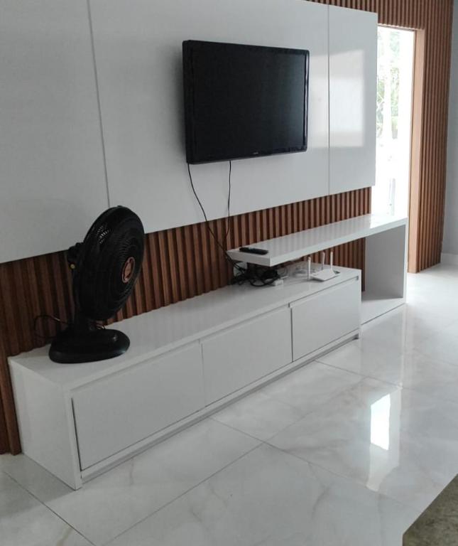a living room with a tv on top of a white cabinet at DR Rbs in Ponta Grossa