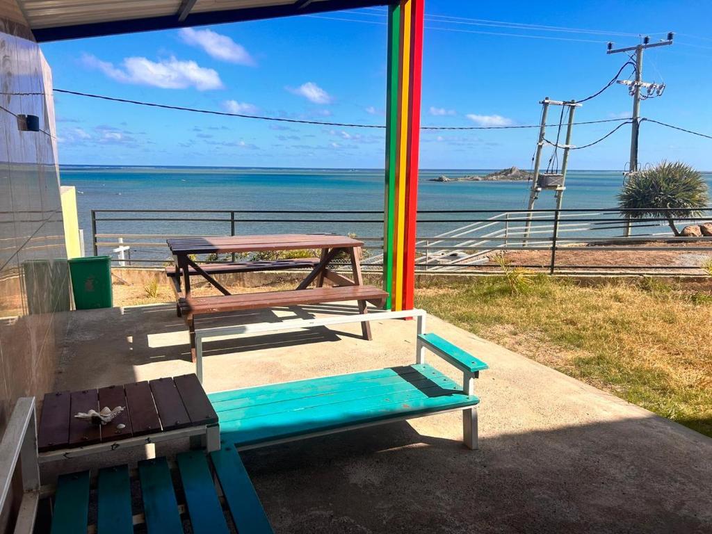 a picnic table and a bench in front of the ocean at EcoDream Lodge in Port Mathurin
